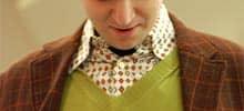 Foto: Person (Lehrer?) mit kariertem Jacket, Pullunder und nervösem Hemd