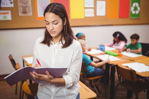 Lehrer korrigiert, während die Schüler arbeiten.