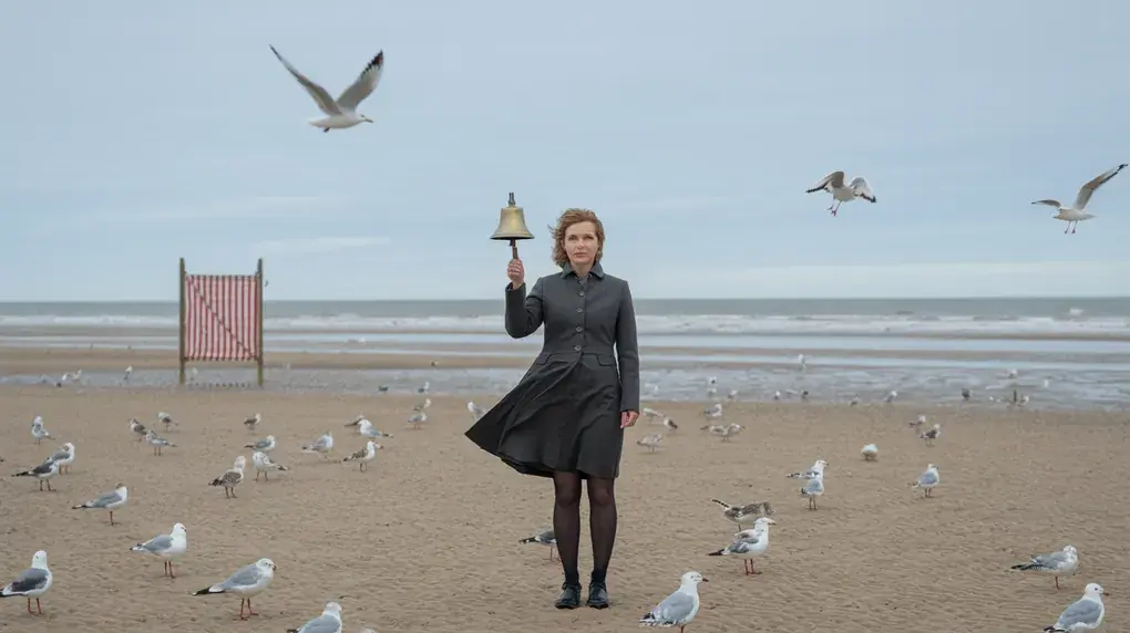 Symbolbild: Lehrerin mit Schulglocke allein am Nordseestrand bei Ebbe