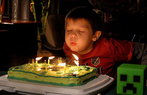 Kind bläst Kerzen auf Geburtstagstorte aus.
